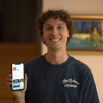 Alexis Bossé tient dans ses mains son téléphone sur lequel on aperçoit l'interface de Lyvio dans le magasin des applications.