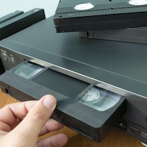 Une personne prend une cassette vidéo qui est insérée dans une machine.