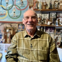 L'homme assis devant des souvenirs de prix qu'il a gagnés, par exemple, des trophées.