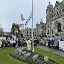 Une personne hisse un drapeau devant des gens rassemblés en cercle.