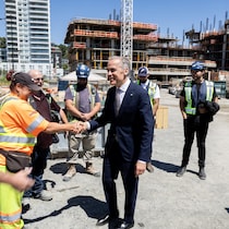Mark Carney serre la main à des ouvriers avec un chantier en arrière-plan.