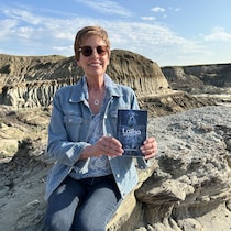 L'autrice Martine Noël-Maw qui tient son livre Laïka, où es-tu? dans les Badlands d'Avonlea en Saskatchewan.