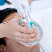 Une personne porte un masque à oxygène.