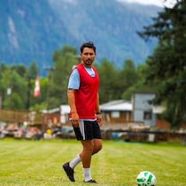 Mateo Kostering qui joue au soccer dans un paysage montagneux.