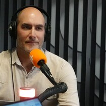 Un homme portant un casque d'écoute en studio devant un micro de Radio-Canada.