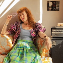 Une femme rousse pose assise sur un canapé.