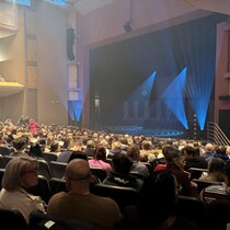 Vue de côté de la salle de spectacle Jean-Marc-Dion. Presque tous les sièges sont occupés (des centaines) et des jeux de lumières animent la scène en attendant le début du spectacle de Messmer.