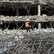 Un travailleur se tient au milieu des décombres pendant que les équipes démolissent le stationnement et le terminal de l'aéroport de Mirabel, le jeudi 20 novembre 2014 à Mirabel, au Québec.