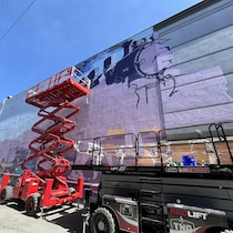 Des nacelles élévatrices à ciseau devant une murale en cours de création.
