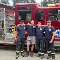 Des pompiers posent devant un camion de pompiers.