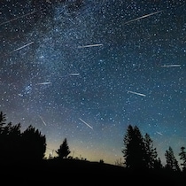 Exposition longue d'un ciel étoilé sur lequel on détecte la voie lactée et des étoiles filantes.