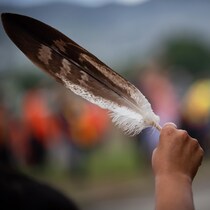 Une femme brandissant une plume d'aigle au passage d'un convoi de camionneurs, en soutien au peuple Tk'emlups te Secwepemc, après la découverte des restes d'enfants enterrés près de l'ancien pensionnat indien de Kamloops, en Colombie-Britannique.