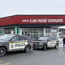 Deux véhicules de police sont stationnés à l'entrée de l'aréna EJM/René-Bernard. 