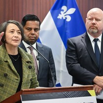 Trois personnes sont debout derrière un lutrin pendant une conférence de presse.