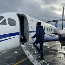 Un homme monte dans un avion, sur le tarmac.