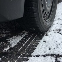 Gros plan sur la roue d'une voiture sur une route enneigée.