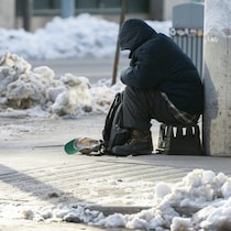 Un homme mendie dans une ville enneigée.
