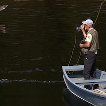 Un pêcheur sur un bateau en train de pêcher.
