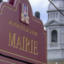 Panneau qui indique l'hôtel de ville. On peut voir le clocher de l'église derrière.