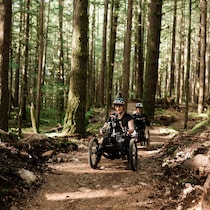 Deux cyclistes en vélo de montagne à trois roues roulent dans un sentier adapté.