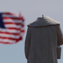 Une statue décapitée et un drapeau américain en arrière-plan