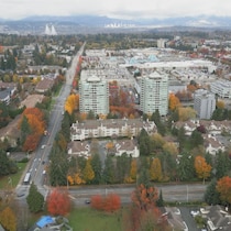 Image de drône d'une partie de la ville de Surrey où l'on voit des immeubles et des édifices entourés d'arbres aux couleurs d'automne, en octobre 2026.
