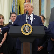 Derrière un lutrin, Donald Trump parle avec des gens derrière lui.