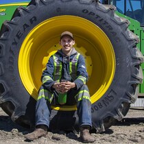 Tyler Didyk assis sur la roue d'un tracteur.