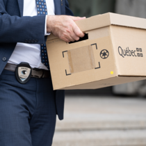 Un agent de police en complet transporte une boîte.
