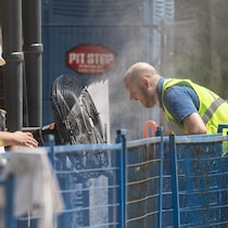 Un travailleur de la construction se penche par en avant pour se rapprocher d'un ventilateur sur son lieu de travail.
