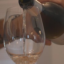 Une main versant du vin dans un verre.