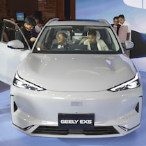 Des gens observent une voiture dans un salon de l'auto.