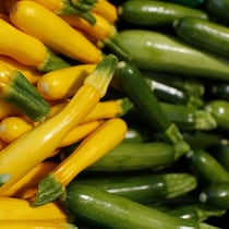 Plan rapproché de dizaines de courgettes parfaitement lisses et empilées, les jaunes à gauche et les vertes à droite.