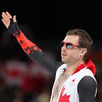 Un patineur lève le bras gauche avec sa combinaison ouverte.