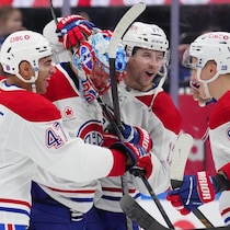 Des hockeyeurs rassemblés autour de leur gardien célèbrent une victoire. 