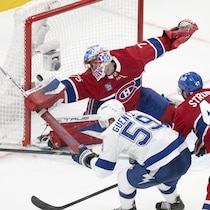 Un hockeyeur marque un but contre un gardien.