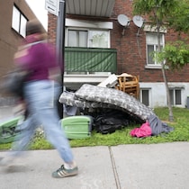 Une personne marche devant un logement avec de nombreux meubles posés juste devant.