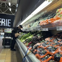 Un commis d'épicerie travaillant dans une allée de fruits et légumes frais. 