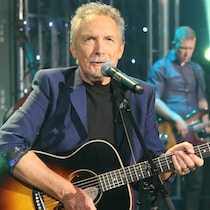 Jacques Michel tient une guitare et chante.