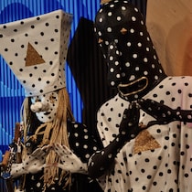 Les membres du groupe, revêtus de déguisements picotés, prennent la pose pour la photo en formant un triangle avec les mains.