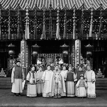 L'impératrice chinoise entourée de 9 personnes, devant un monument chinois.