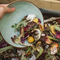 Une femme met au compost des restants des aliments.