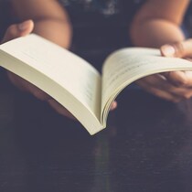 Une personne tient un livre ouvert dans ces mains.