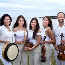 Une famille (trois jeunes femmes entournées de leurs parents) dont les membres sont vêtus en blanc. On voit une grande étendue d'eau derrière eux.