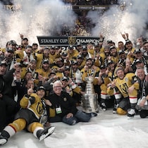 Les joueurs et les membres du personnel des Golden Knights prennent une photo d'équipe avec la coupe Stanley au centre de la patinoire, après leur victoire en finale.