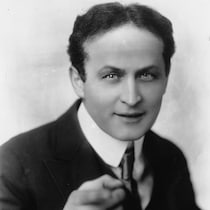 L'illusionniste Harry Houdini, en complet cravate, regarde la caméra.