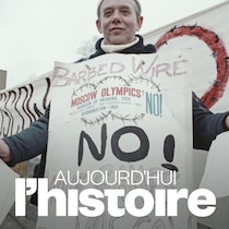 Un homme porte une affiche demandant le boycottage des Jeux olympiques de Moscou et tient des feuilles dans ses mains.