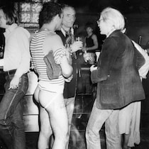 À droite, l'artiste visuel Andy Warhol discute avec deux hommes au Studio 54.