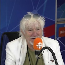 Hugues Aufray derrière un micro dans un studio radio de Radio-Canada.