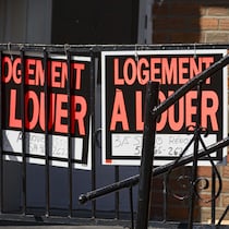 Des panneaux de logement à louer sur une rambarde de balcon en fer forgé.